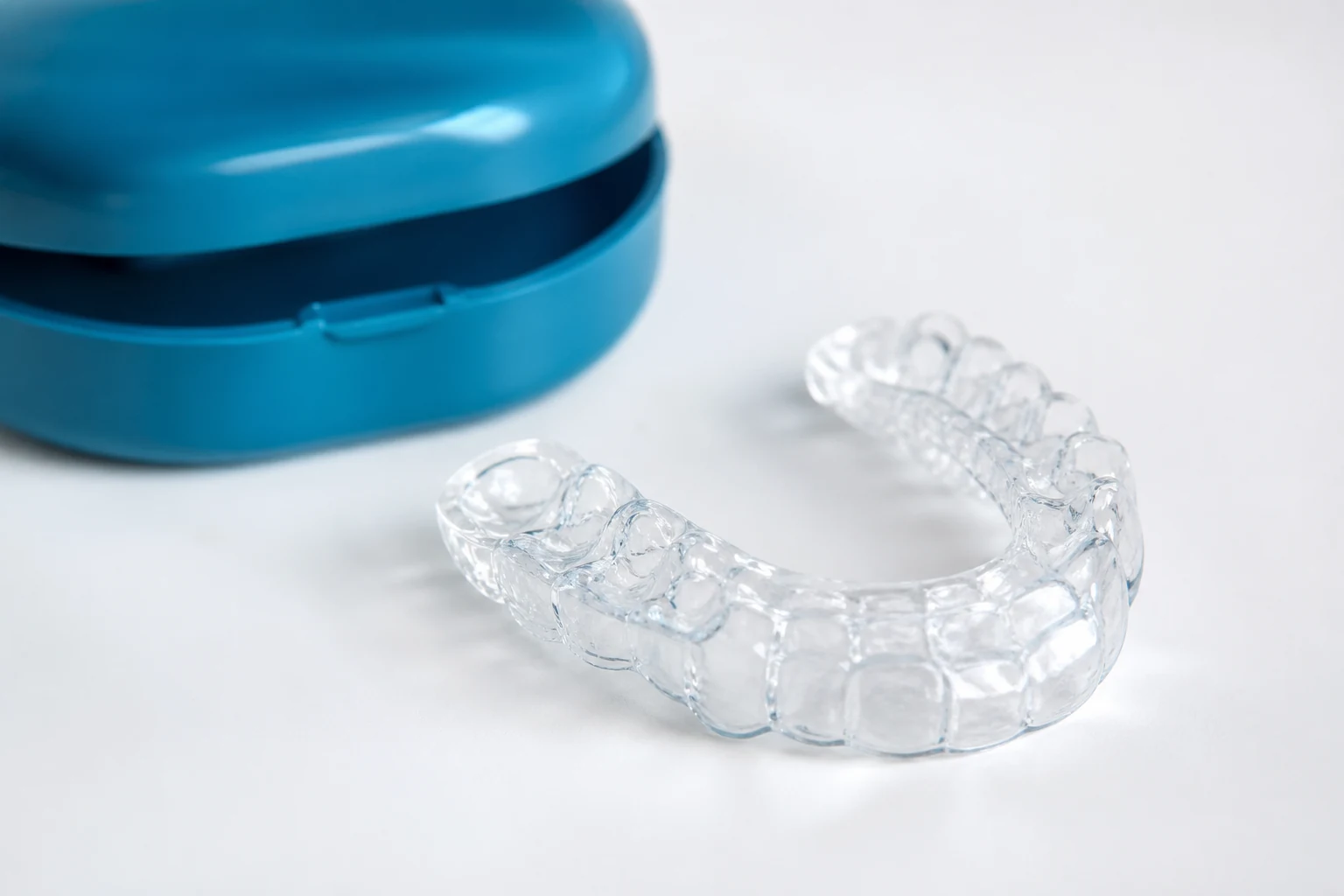 Clear custom dental night guard beside a teal storage case